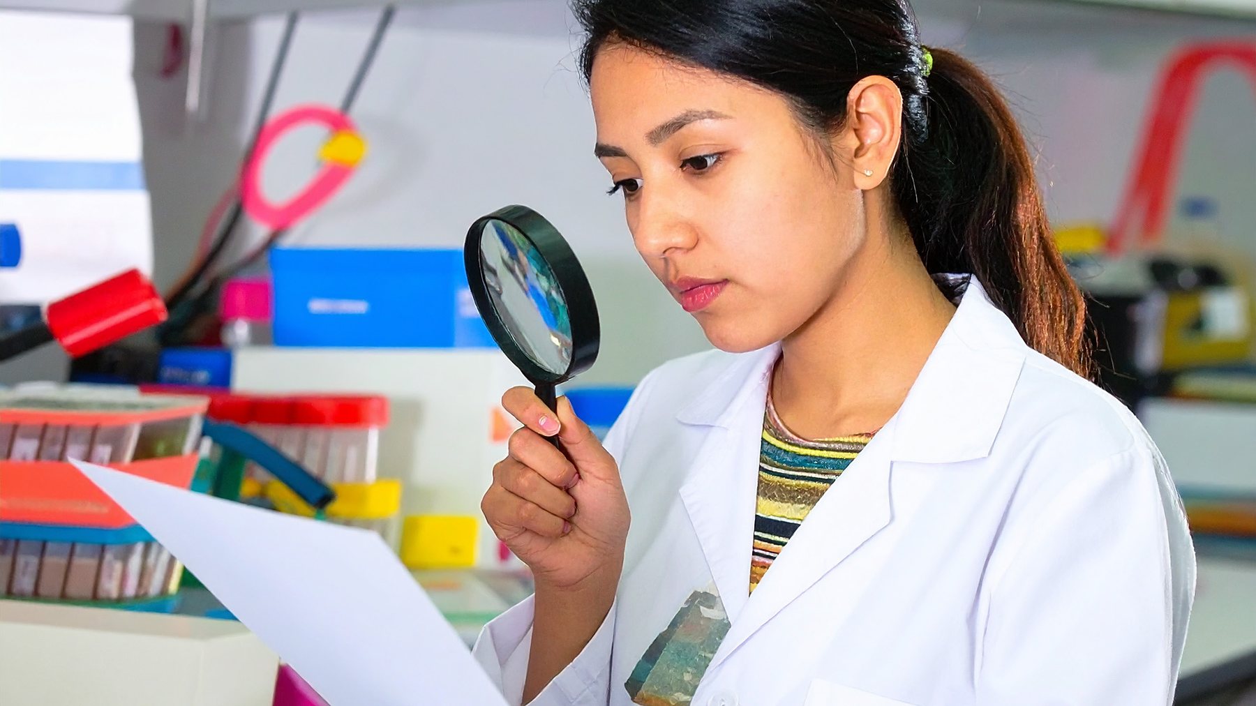 A printed sheet being inspected under a magnifier in the quality lab